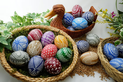 Baskets of brightly colored, patterned Easter eggs arranged with greenery, representing festive Easter traditions.